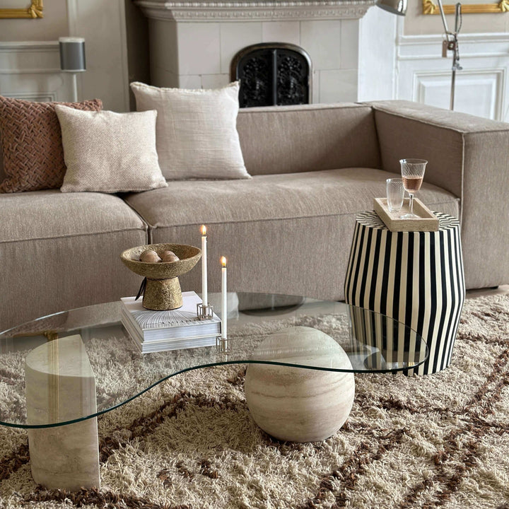 Elegant stue med beige sofa, glaskaffebord og moderne dekorationer, produceret i europa.